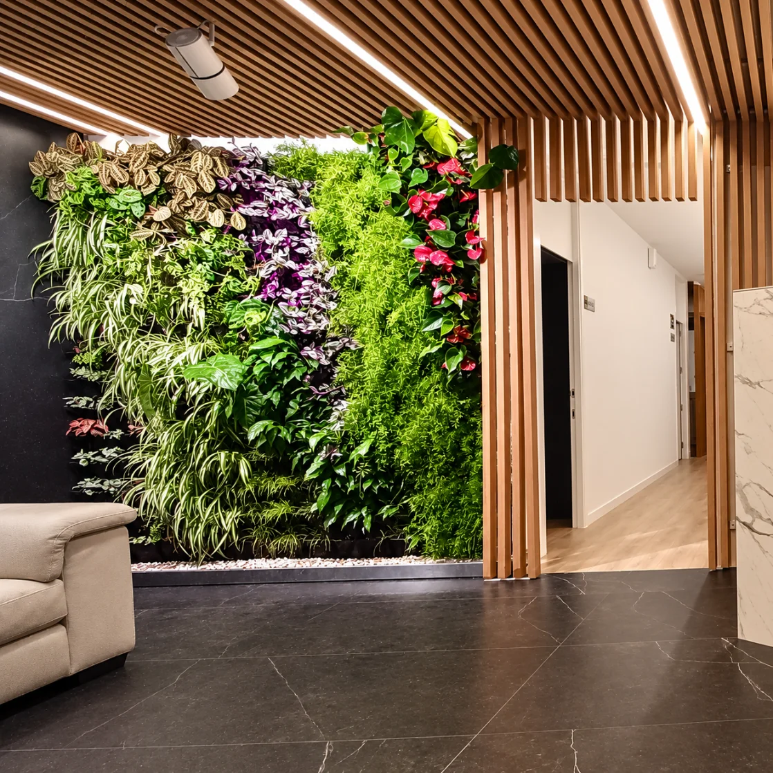 Large indoor living wall in a bright, open hall with timber flooring and a green sofa